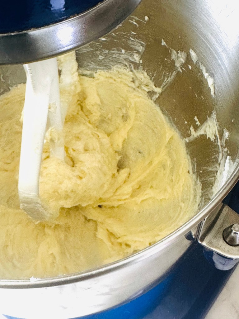 A photo of cream cheese and sugar being mixed together in a mixer