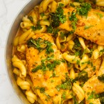 A large pan of Marry Me Chicken nestled with pasta and a garnish of parsley