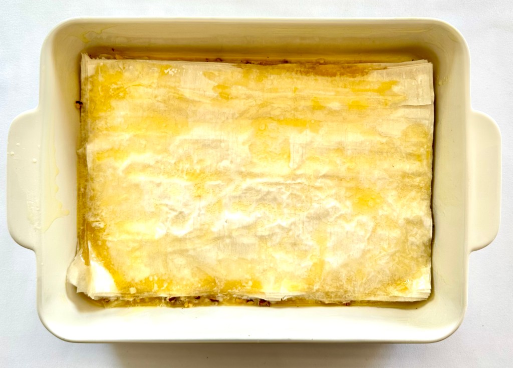 A baking pan layered with sheets of phyllo and melted butter on top