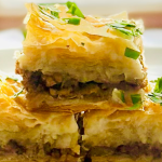 Individual slices of savory baklava with beef and onion, garnished with parsley