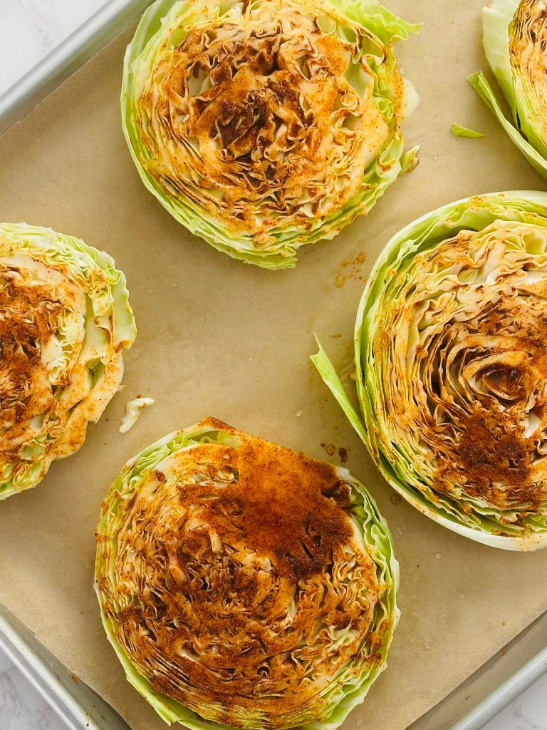 A baking sheet of cabbage steaks brushed with a garlic oil mixture