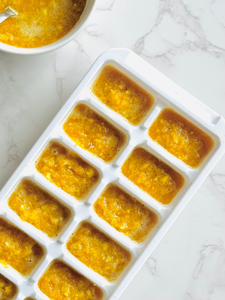 An ice cube tray filled with a mixture of citrus, ginger, and spices for a make-ahead cold relief tea