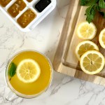 A glass cup filled with a homemade cold remedy of tea made with citrus and ginger