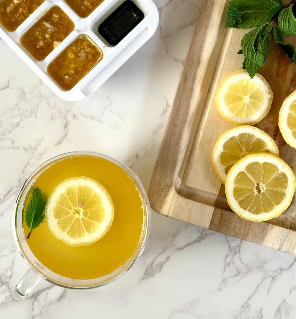 A glass cup filled with a homemade cold remedy of tea made with citrus and ginger