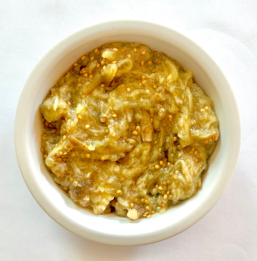 A bowl of eggplant flesh and seeds scooped out of a roasted eggplant