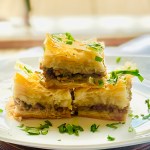 Individual slices of savory baklava with beef and onion, garnished with parsley