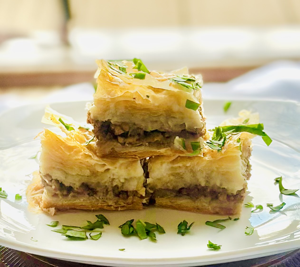 Individual slices of savory baklava with beef and onion, garnished with parsley