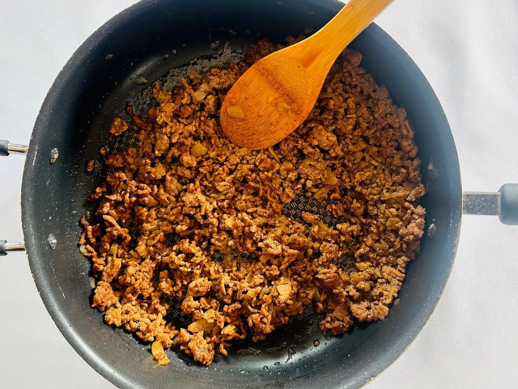 Ground beef being sauteed in a pan with spices