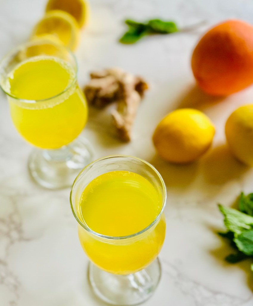 Two glass cups filled with a homemade cold remedy of tea made with citrus and ginger