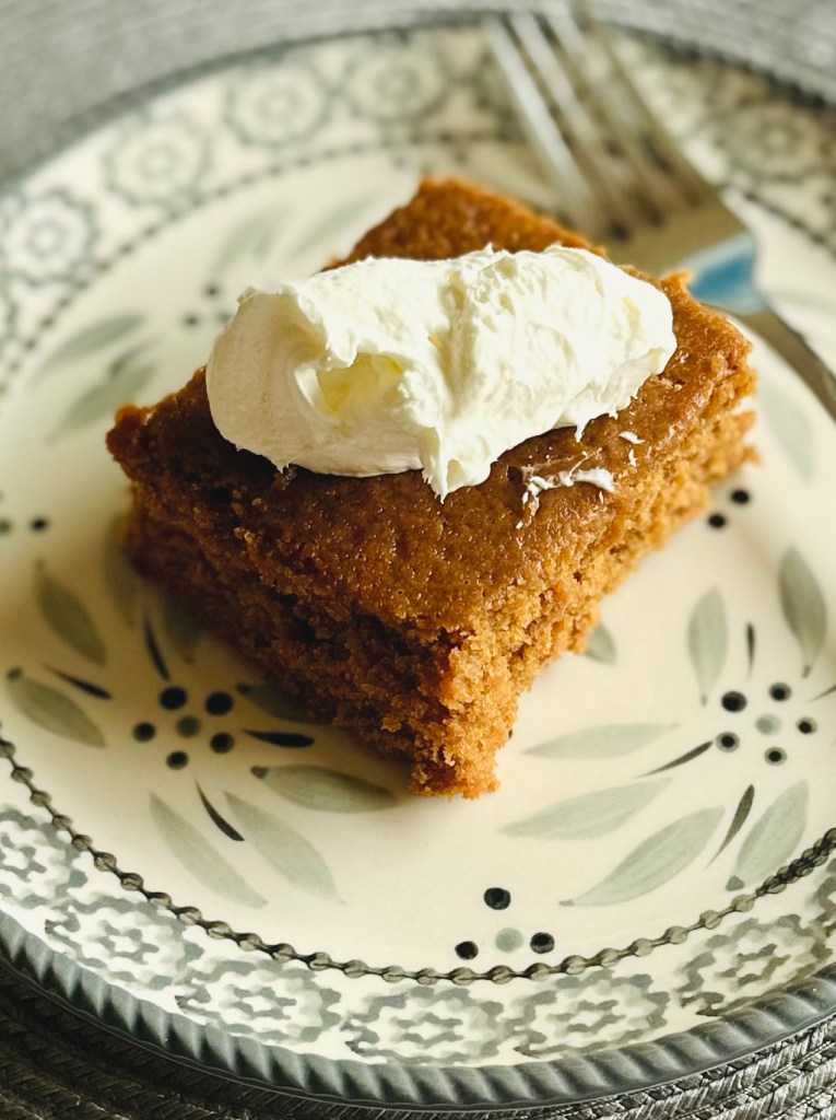 A slice of homemade molasses cake with whipped cream