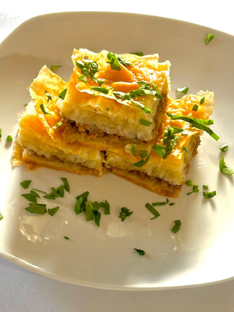 Individual slices of savory baklava with beef and onion, garnished with parsley