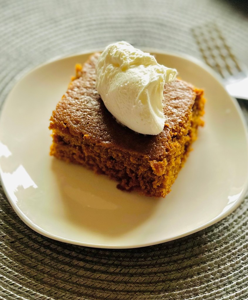 A slice of homemade molasses cake with whipped cream