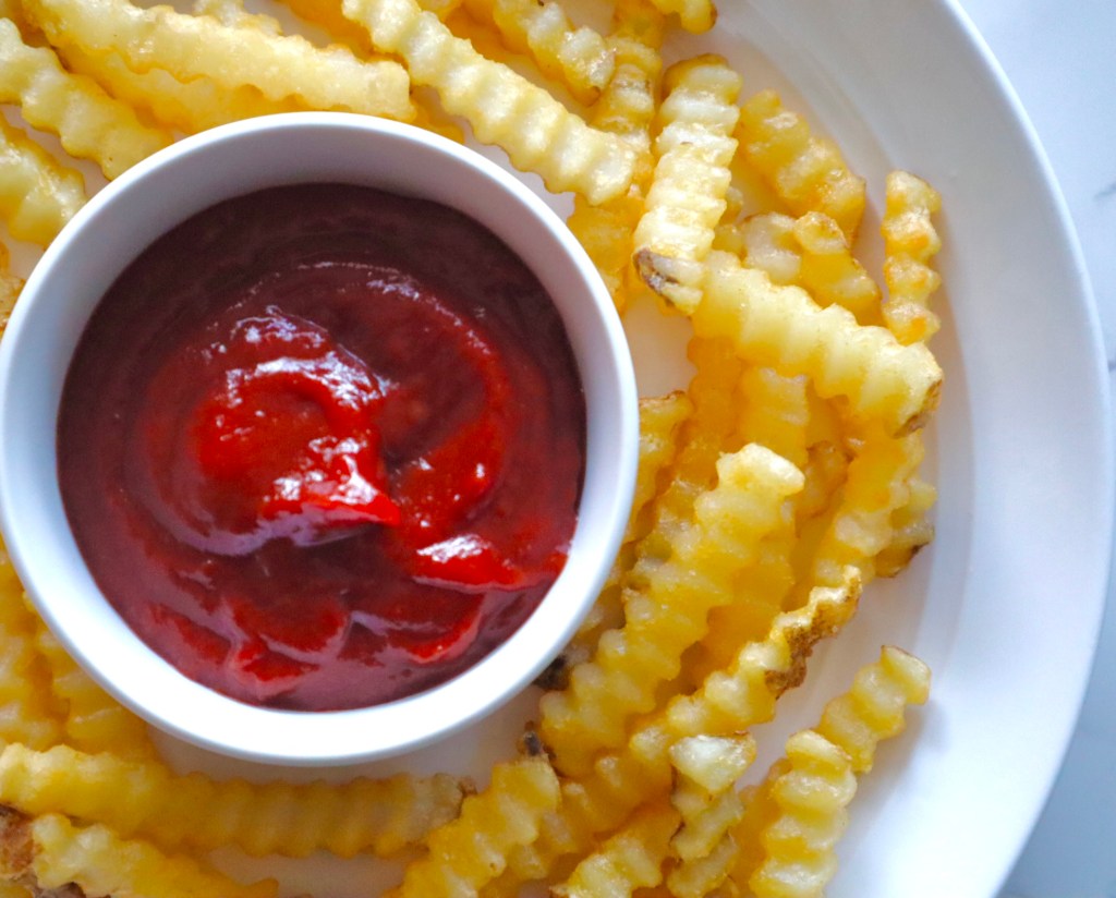A bowl of homemade ketchup served alongside crinkle-cut fries