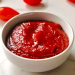 A bowl of homemade ketchup with cherry tomatoes in the background