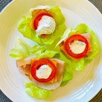 Lettuce wraps on a plate topped with turkey lunchmeat, cheddar cheese, roma tomatoes, and a dill-yogurt dressing