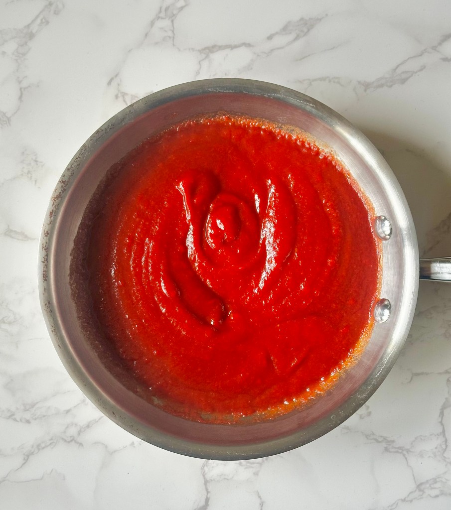 Saucepan full of tomato paste, water, and various spices to make homemade ketchup