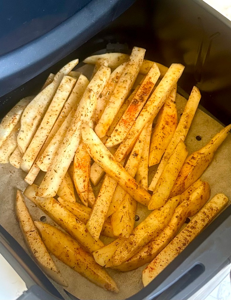 Preparing seasoned French fries in an air fryer basket