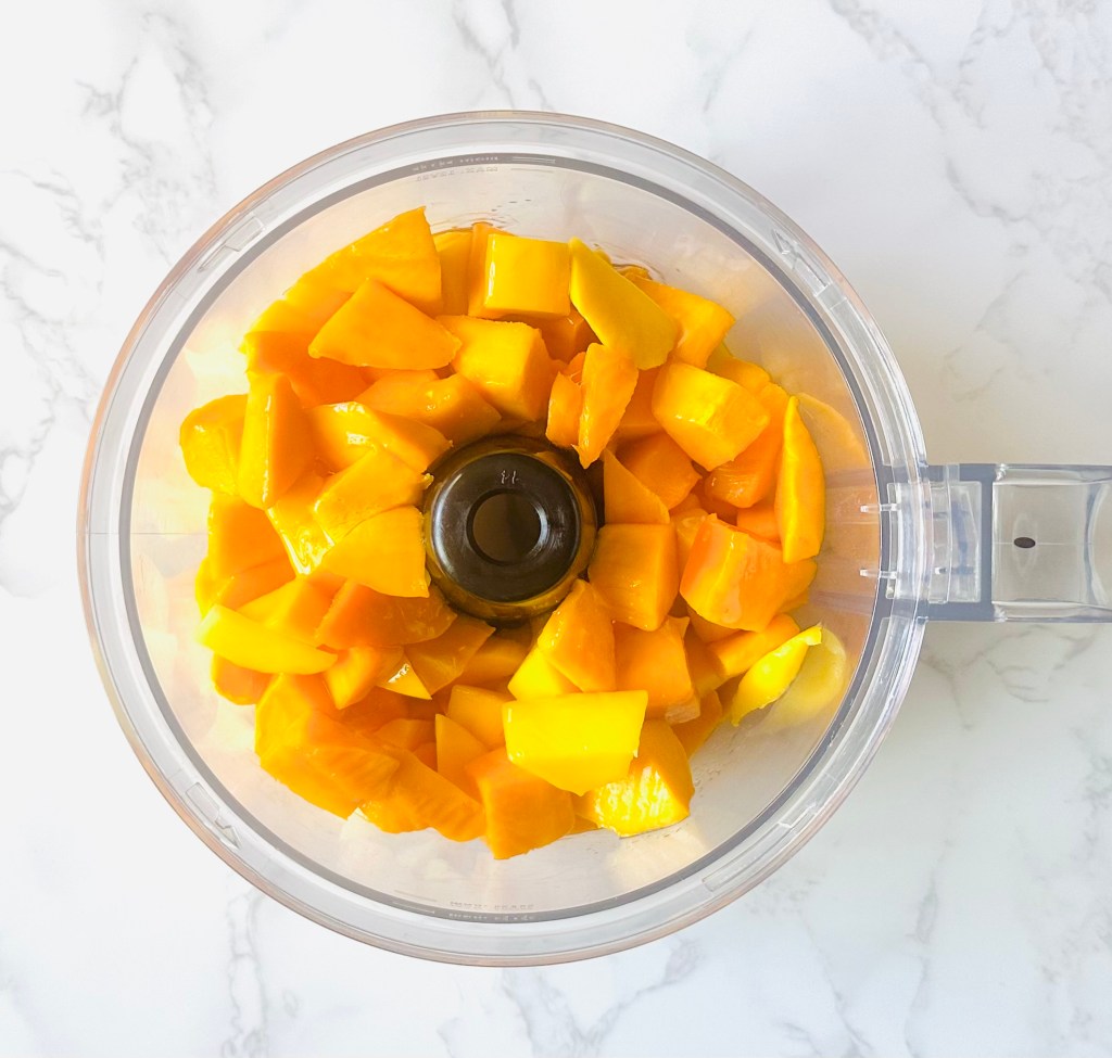 Cut mango slices inside the bowl of a food processor