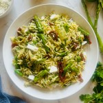 Photo of a bowl filled with homemade orzo pasta salad with asparagus and sun-dried tomatoes