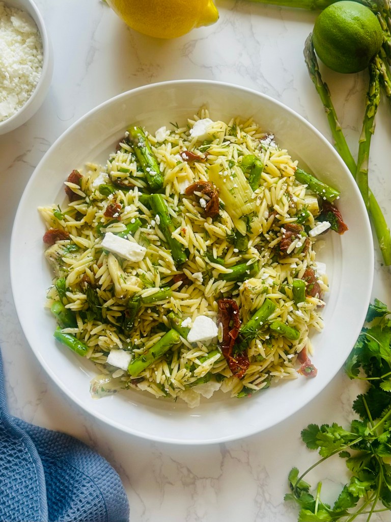 Photo of a bowl filled with homemade orzo pasta salad with asparagus and sun-dried tomatoes