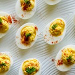 A platter of deviled eggs garnished with paprika and parsley