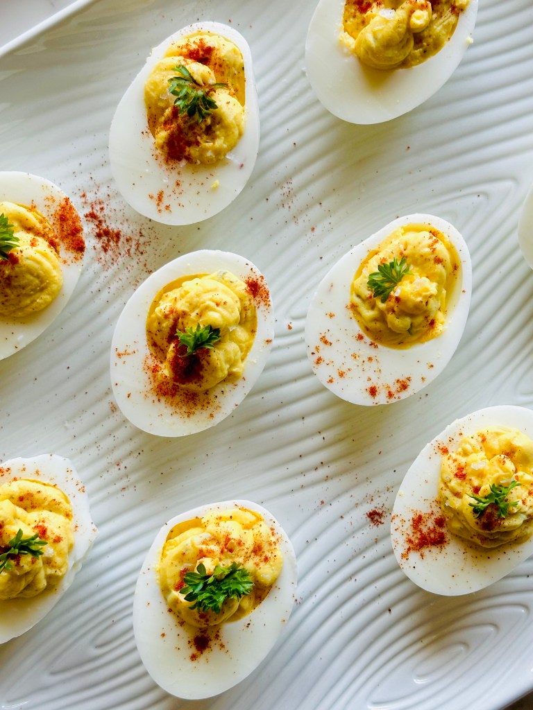 A platter of deviled eggs garnished with paprika and parsley
