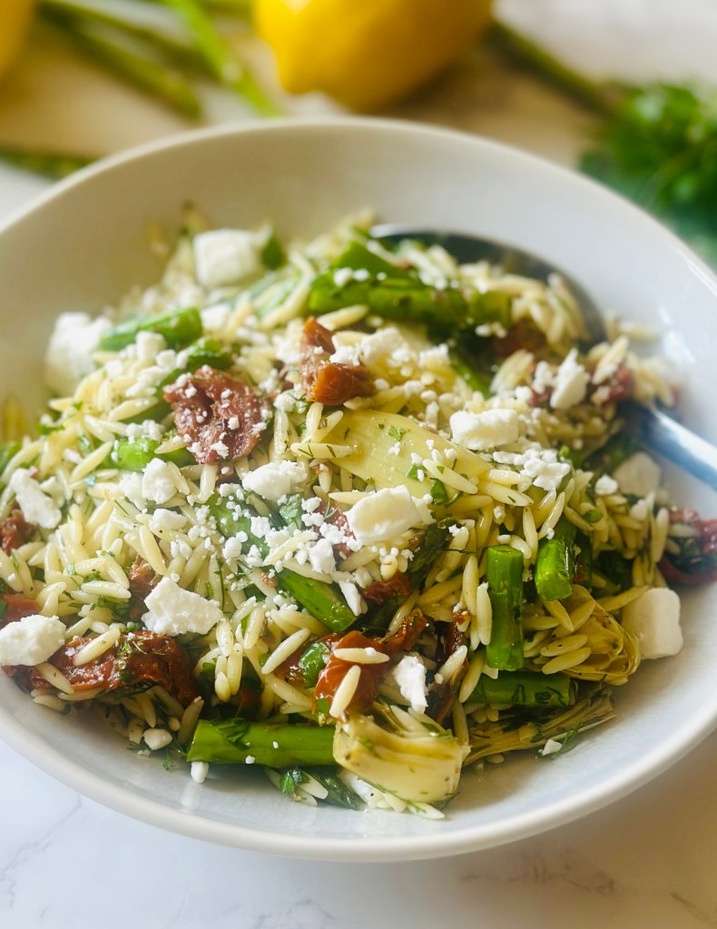 Photo of a bowl filled with homemade orzo pasta salad with asparagus and sun-dried tomatoes