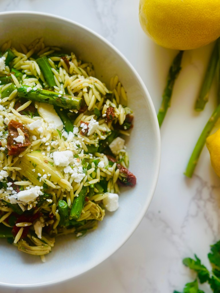 Photo of a bowl filled with homemade orzo pasta salad with asparagus and sun-dried tomatoes