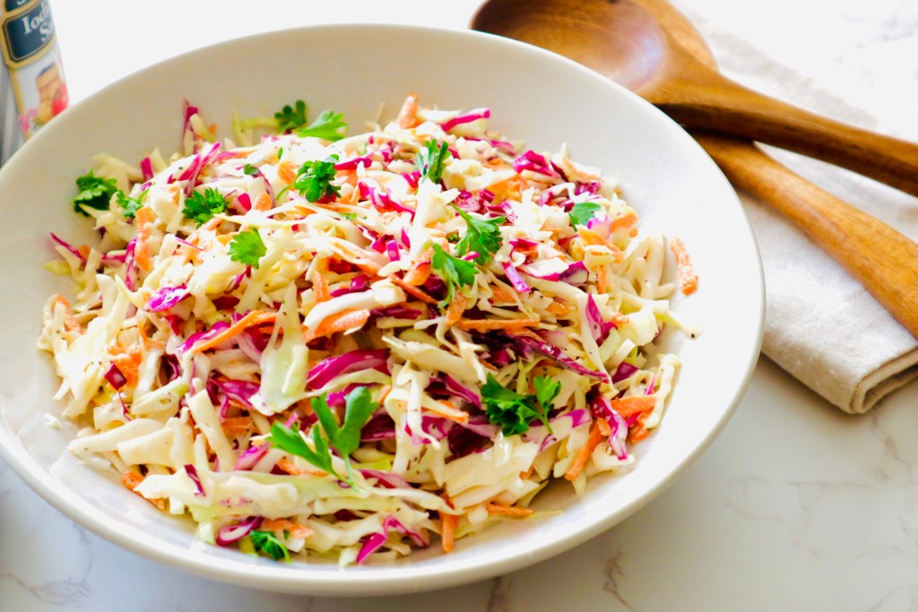 Homemade coleslaw made with shredded green cabbage, red cabbage, and carrots, tossed with a dressing of mayo, vinegar, sugar, celery seed, salt, and pepper