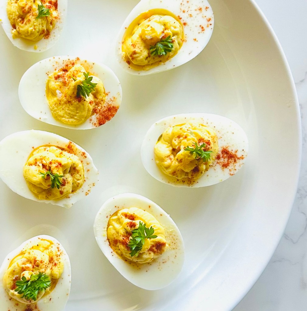 A platter of deviled eggs garnished with paprika and parsley