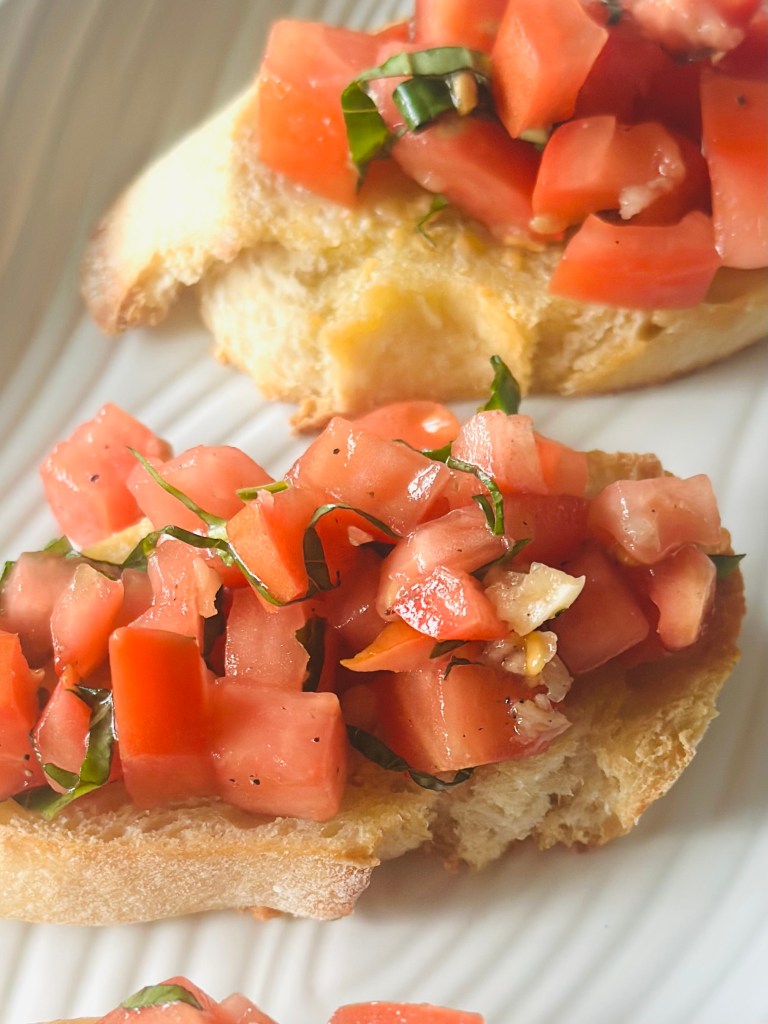 Baguette slices topped with a homemade tomato basil topping, drizzled with olive oil, and sprinkled with salt