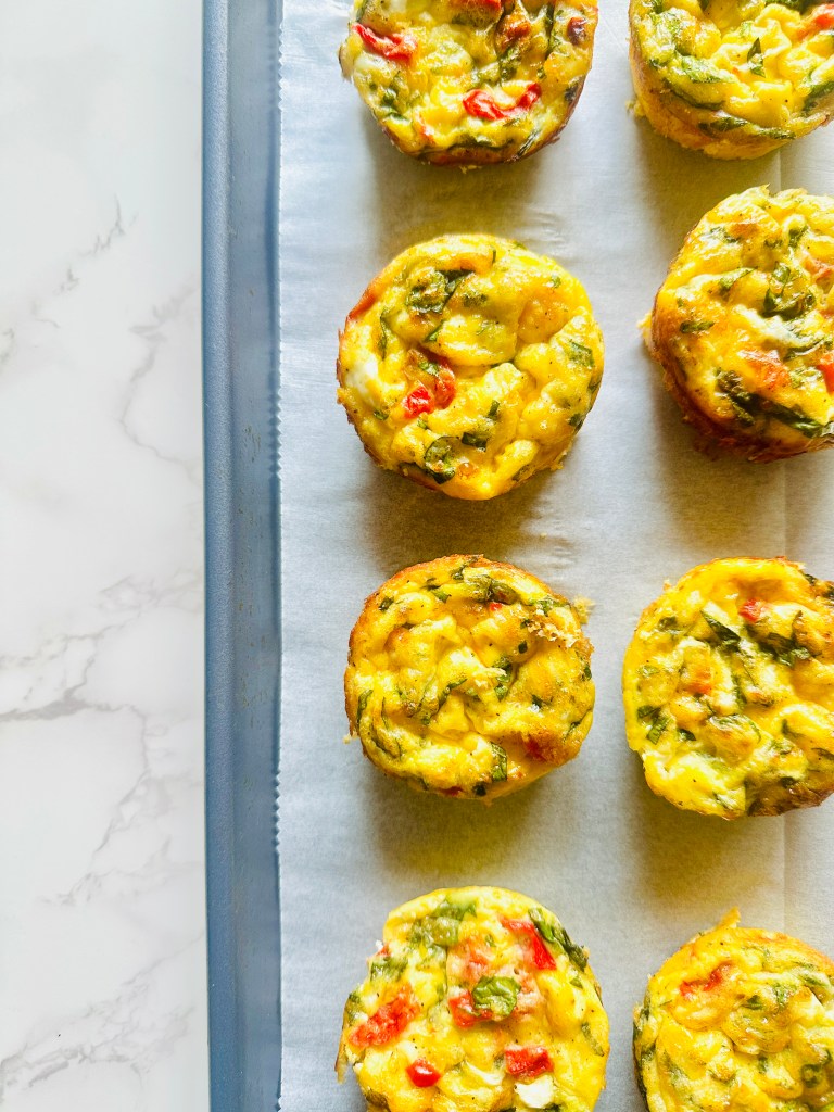 A baking sheet with parchment paper that is filled with homemade cottage cheese egg bites