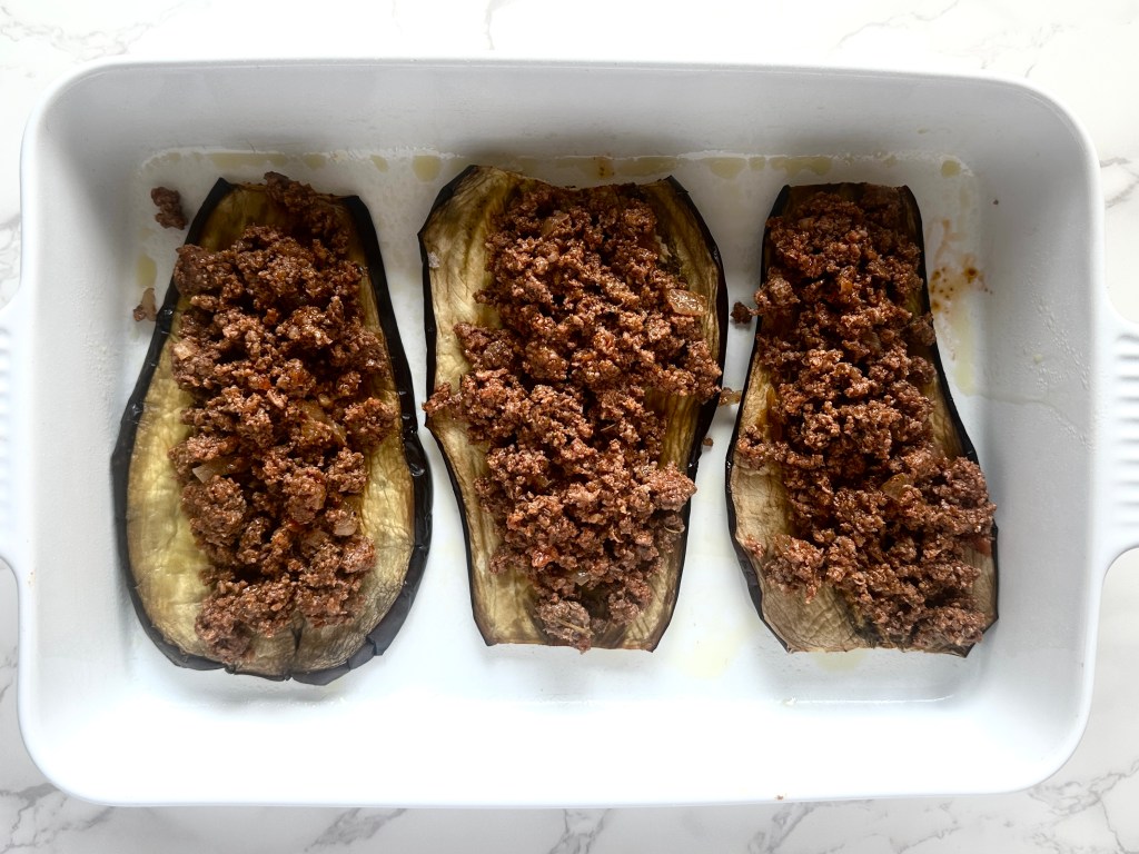 A baking dish with roasted eggplant, layered with a mixture of ground beef, onion, and spices
