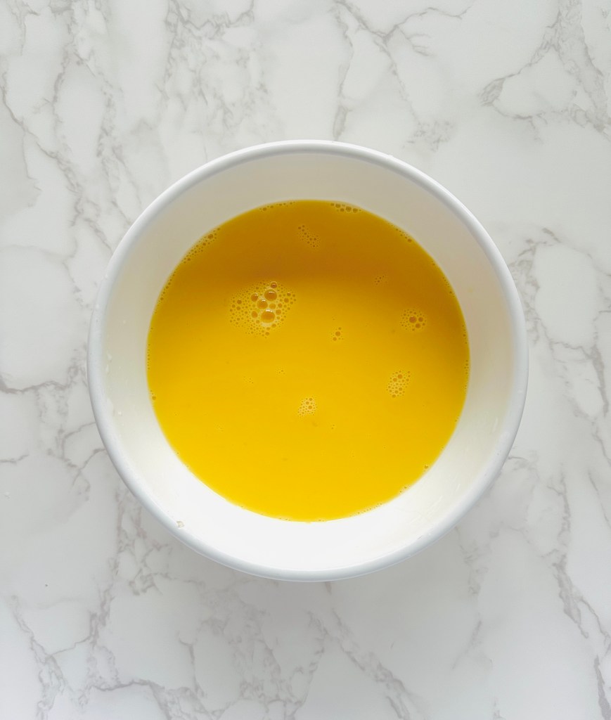 A small bowl of eggs and chicken broth whisked together