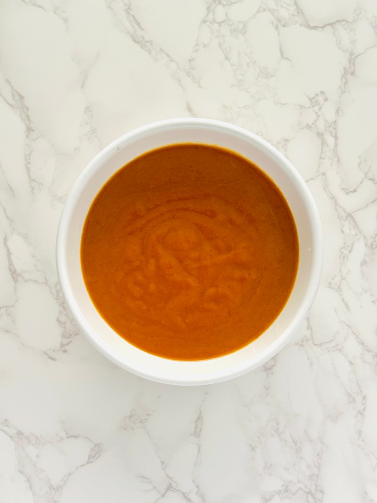 A photo of wet ingredients in a bowl for pumpkin cupcakes: brown sugar, pumpkin puree, olive oil, and eggs