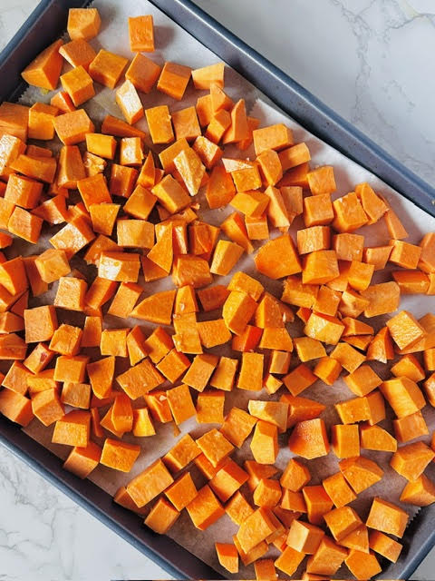 A baking sheet full of oven-roasted sweet potatoes seasoned with olive oil and salt